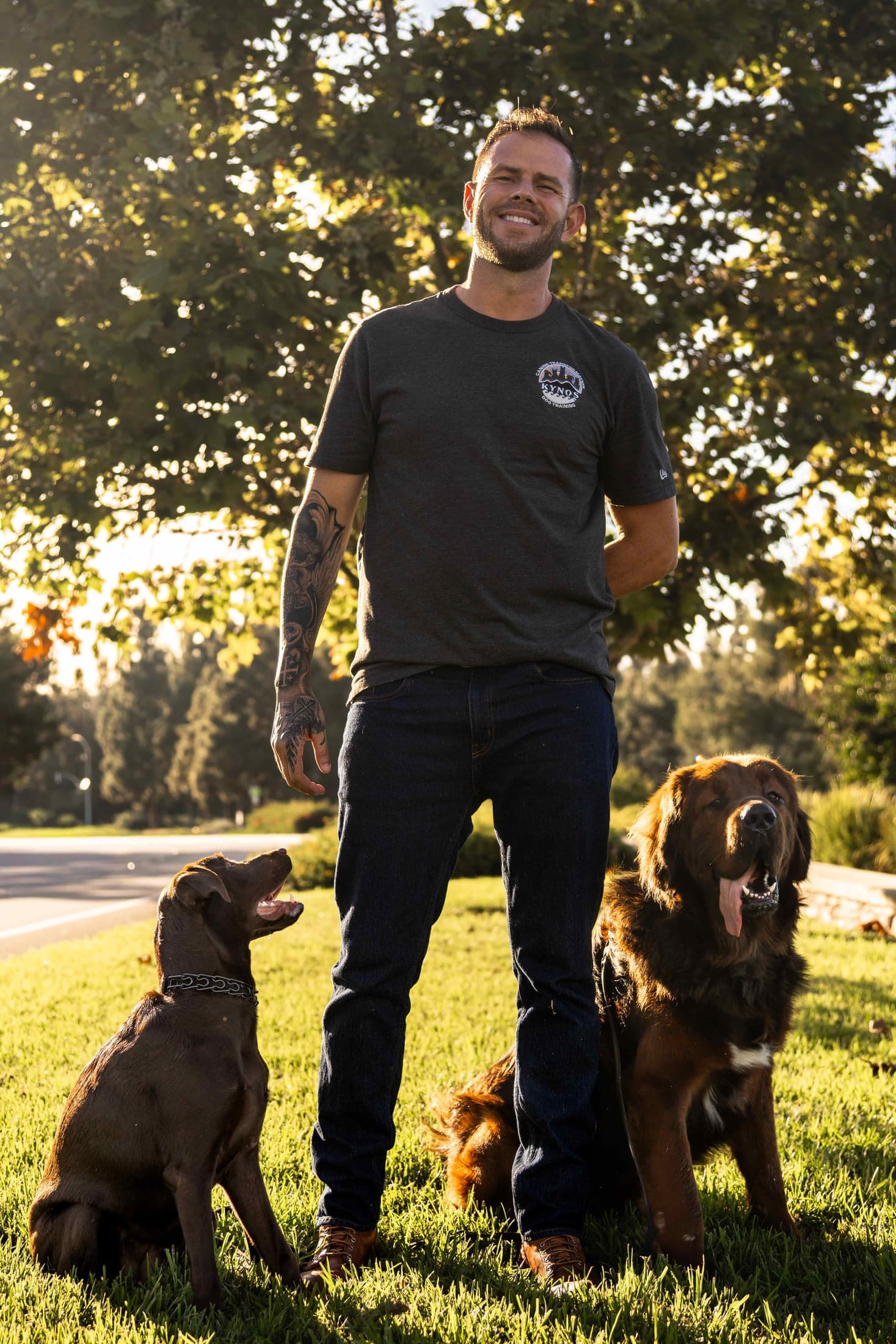 Jake, the Kynos lead trainer, with two dogs at golden hour
